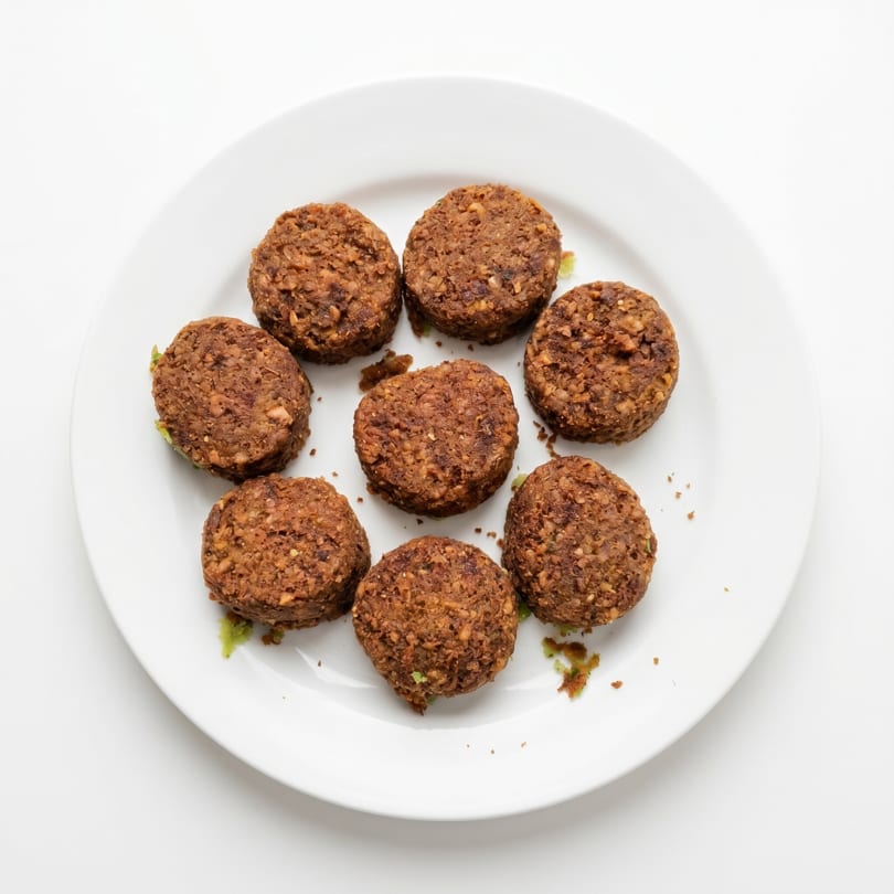Eight crispy, brown falafel patties arranged on a white plate, viewed from above.